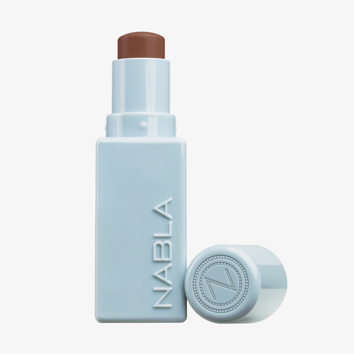 Ein hellblauer NABLA Cosmetics Contour Stick mit abgenommener Kappe, die die braune Konturenfarbe zeigt.