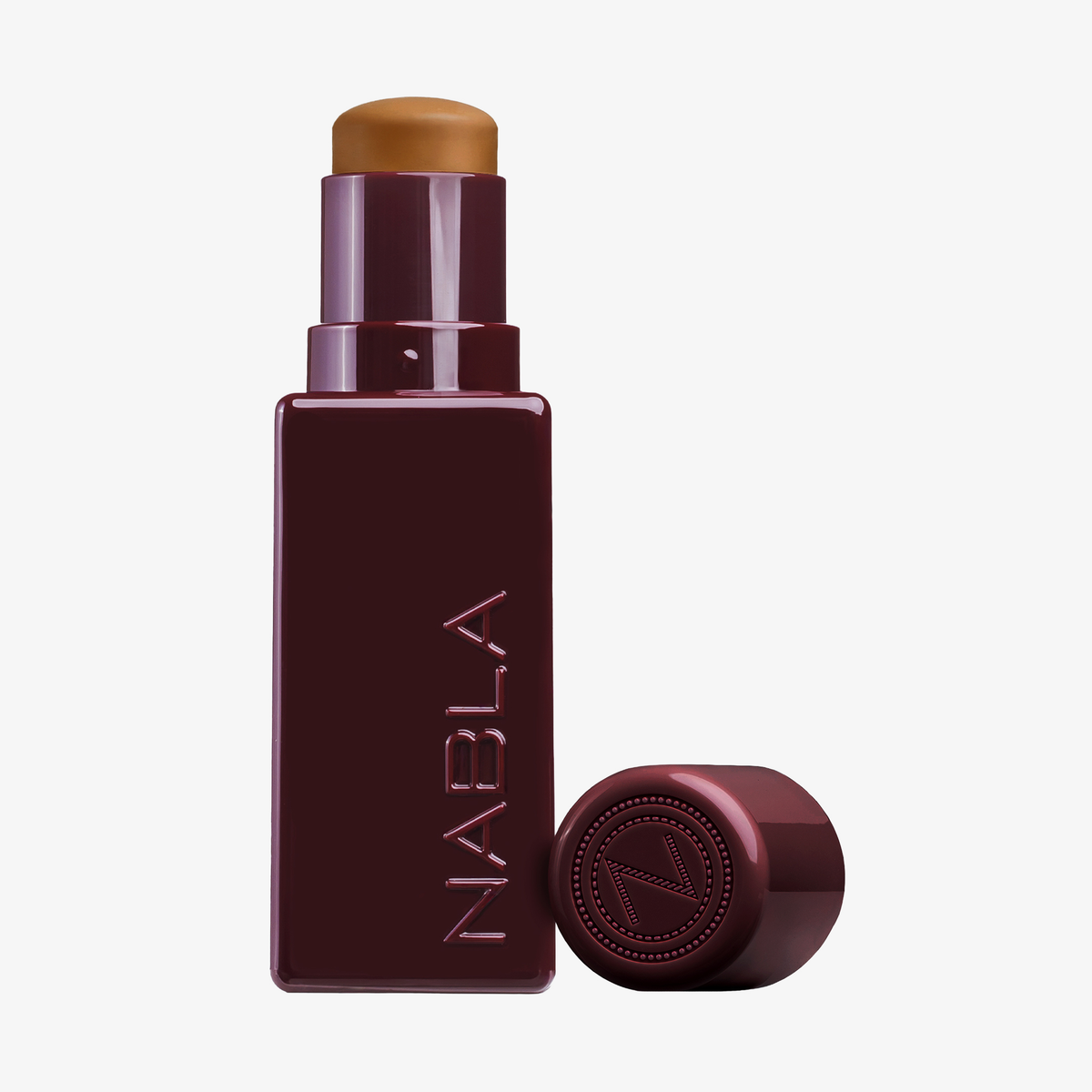 Ein kastanienbrauner NABLA Cosmetics Art Of Skin Foundation Stick mit abgenommener Kappe gibt den Blick auf das Produkt frei, das sich vor einem hellen Hintergrund befindet.