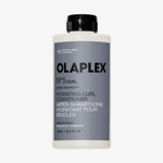 Eine Flasche OLAPLEX N°5 CURL Bond Shaper Hydrating Curl Conditioner mit grauem Etikett und schwarzem Verschluss.