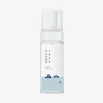 1025 Dokdo Bubble Foam von ROUND LAB kommt in einer durchsichtigen Flasche mit einer weißen Pumpe und einem Etikett mit blauem Wasser, Felsen und koreanischem Text.