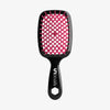 Die UNbrush Detangling Hair Brush hat ein schwarzes Paddle-Design mit rosa Borsten und einem sechseckigen Loch im Griff.