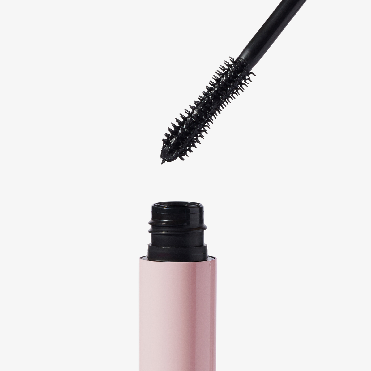 Die Bürste der XLASH Lash Hero Mascara schwebt über einer offenen, rosa Tube vor einem weißen Hintergrund.