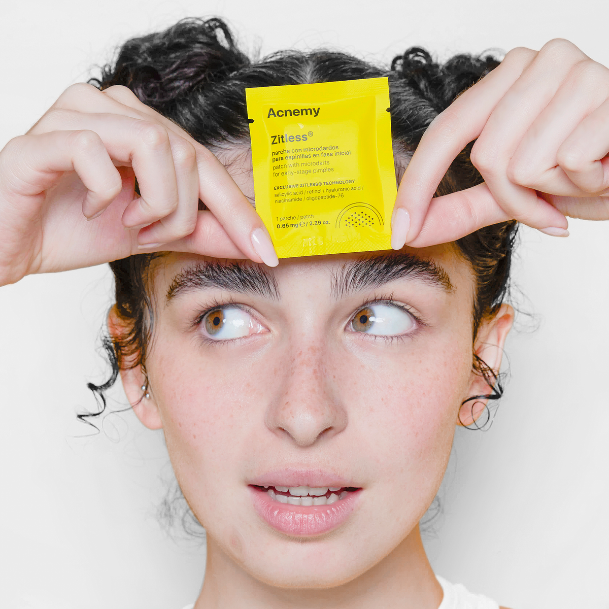 Eine Person hält eine gelbe Packung Zitlessvor die Stirn, blickt mit neutralem Gesichtsausdruck zur Seite 