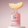Eine Pfirsichscheibe liegt auf einer offenen Flasche Peach 70 % Niacinamide Serum vor einem zartrosa Hintergrund.