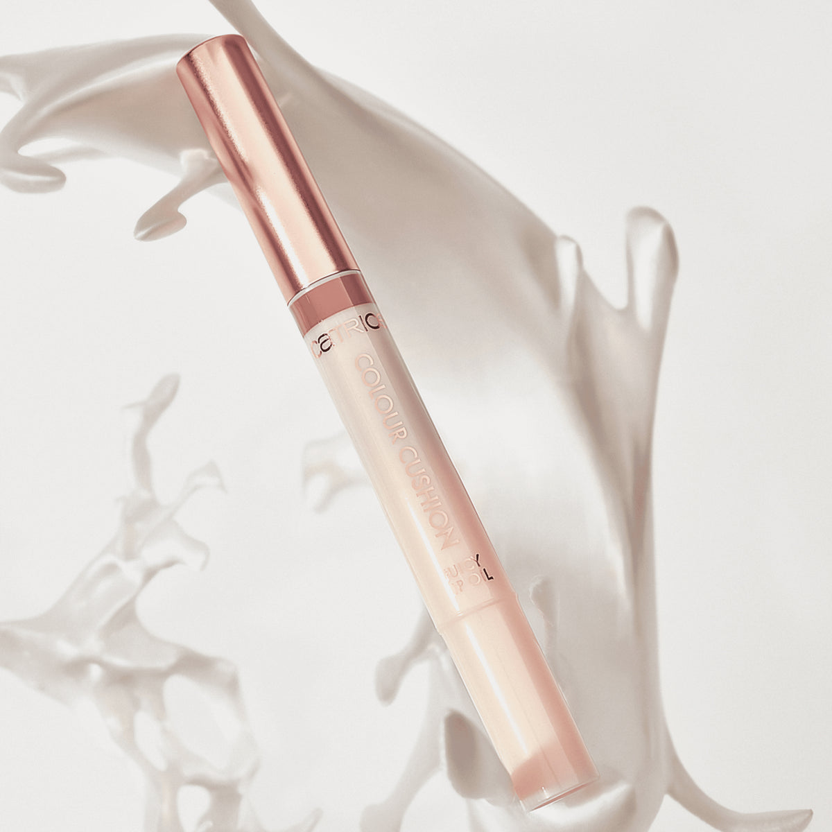 Catrice Colour Cushion Juicy Lip Oil in elegantem Nude-Design mit roségoldenem Deckel, vor einem weißen Hintergrund mit schwungvollen Strukturen.