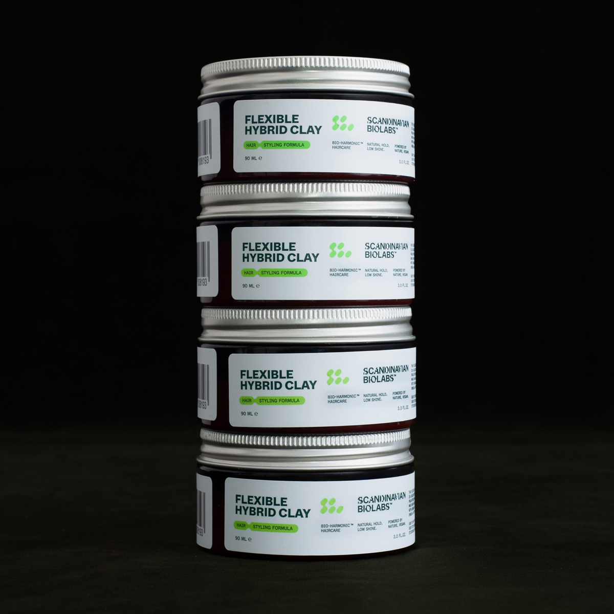 Gestapelte Dosen des Scandinavian Biolabs Flexible Hybrid Clay Stylingprodukts vor dunklem Hintergrund.“