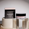 Evolution Powder Pink von Danessa Myricks Beauty mit Schachtel, ausgestellt auf geometrischen Steinplattformen unter sanfter Beleuchtung.