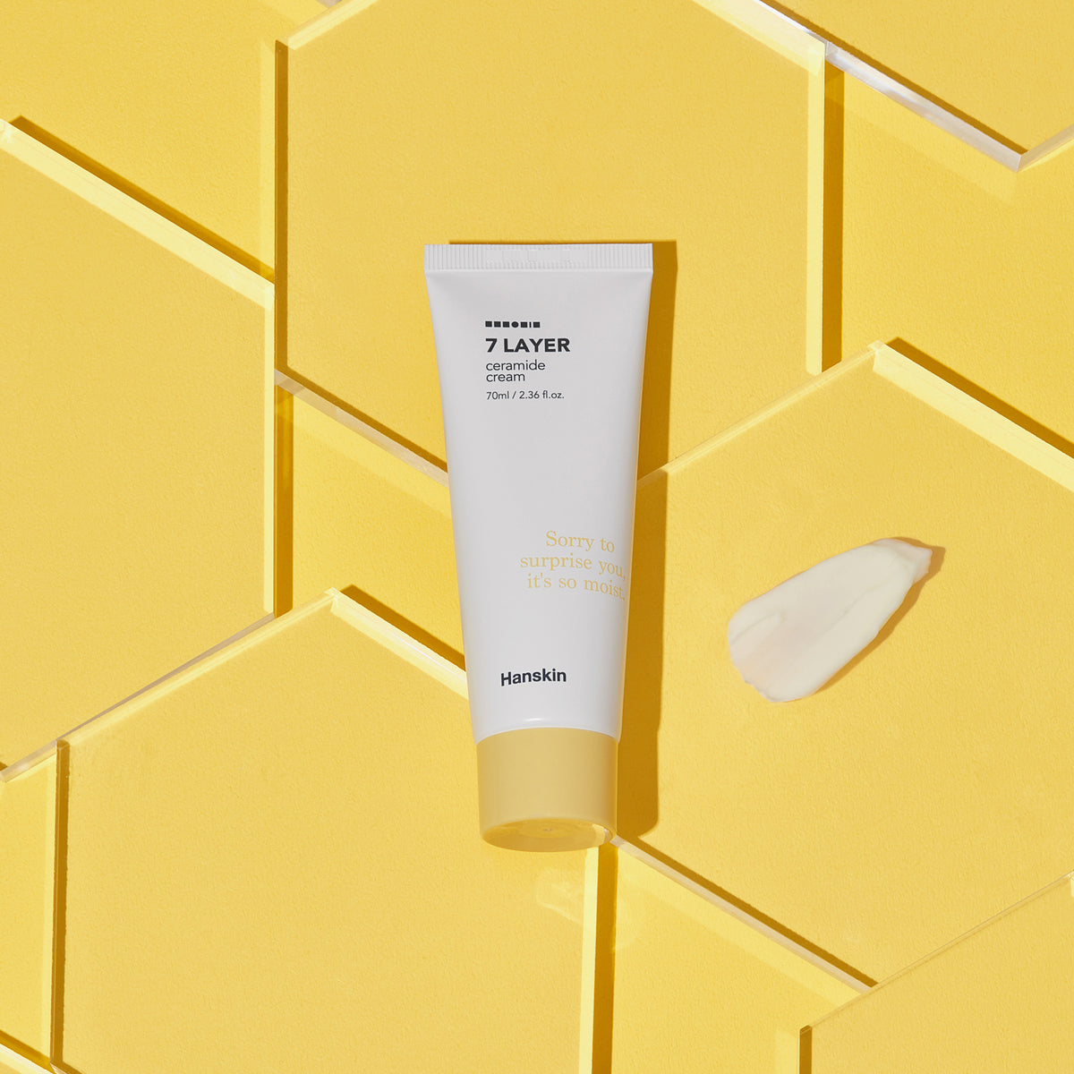 Seven Layer Ceramide Cream-Tube und ein Klecks Creme auf gelbem geometrischem Hintergrund.