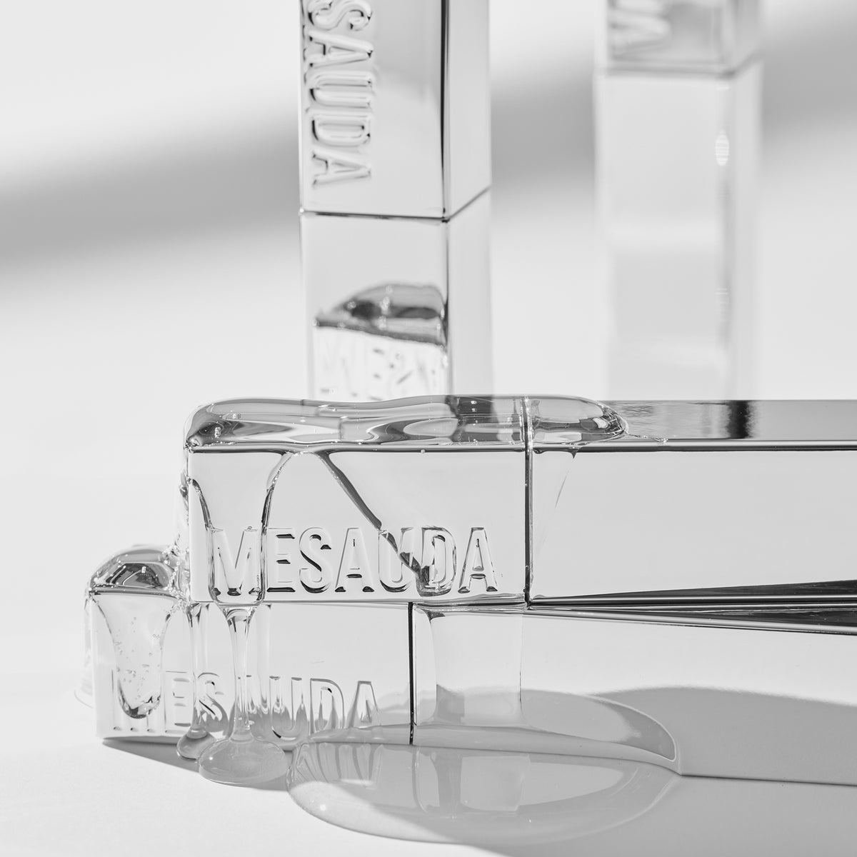 Klare Produktmasse des LIP PHENOM™ von Mesauda Beauty auf verschlossenen silbernen Produkttuben auf einer spiegelnden Oberfläche.