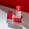 Flasche mit Vitamin A Glow Retinol Serum und zwei rot-weißen Produktboxen auf hellem Untergrund.