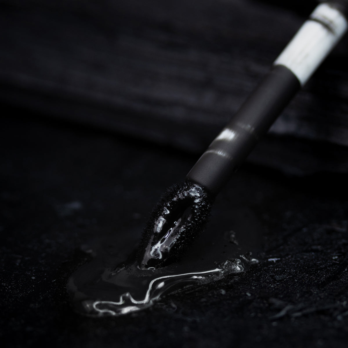 Ein Shadow Potion Paint Black Base Eclipse-Applikator wird in eine glänzende auf einer schwarzen Oberfläche dargestellt.