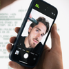 Eine Person macht ein Selfie, während sie Scandinavian Biolabs Bio-Pilixin® Hairline Booster mit einem schwarzen Gerät auf ihren Haaransatz aufträgt.