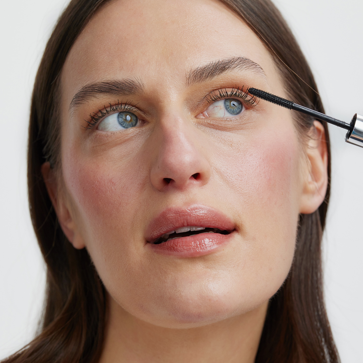 Eine Person, die mit einem Applikator die XLASH Lash Booster-Mascara auf ihre oberen Wimpern aufträgt.