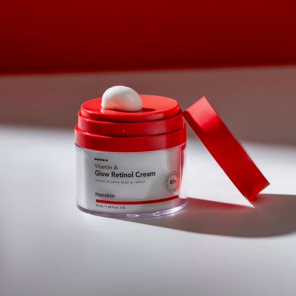 Offener Tiegel mit Vitamin A Glow Retinol Cream, mit einem Klecks Creme auf dem roten Spender.