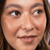 Nahaufnahme des Gesichts einer Person mit gebräunten Wangen die zur Seite blickt und lächelt