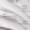 Nahaufnahme der weißen Creme Everyday Gradual Tan mit Etiketten, auf denen Sheabutter, Glycerin und Vitamin E hervorgehoben sind.