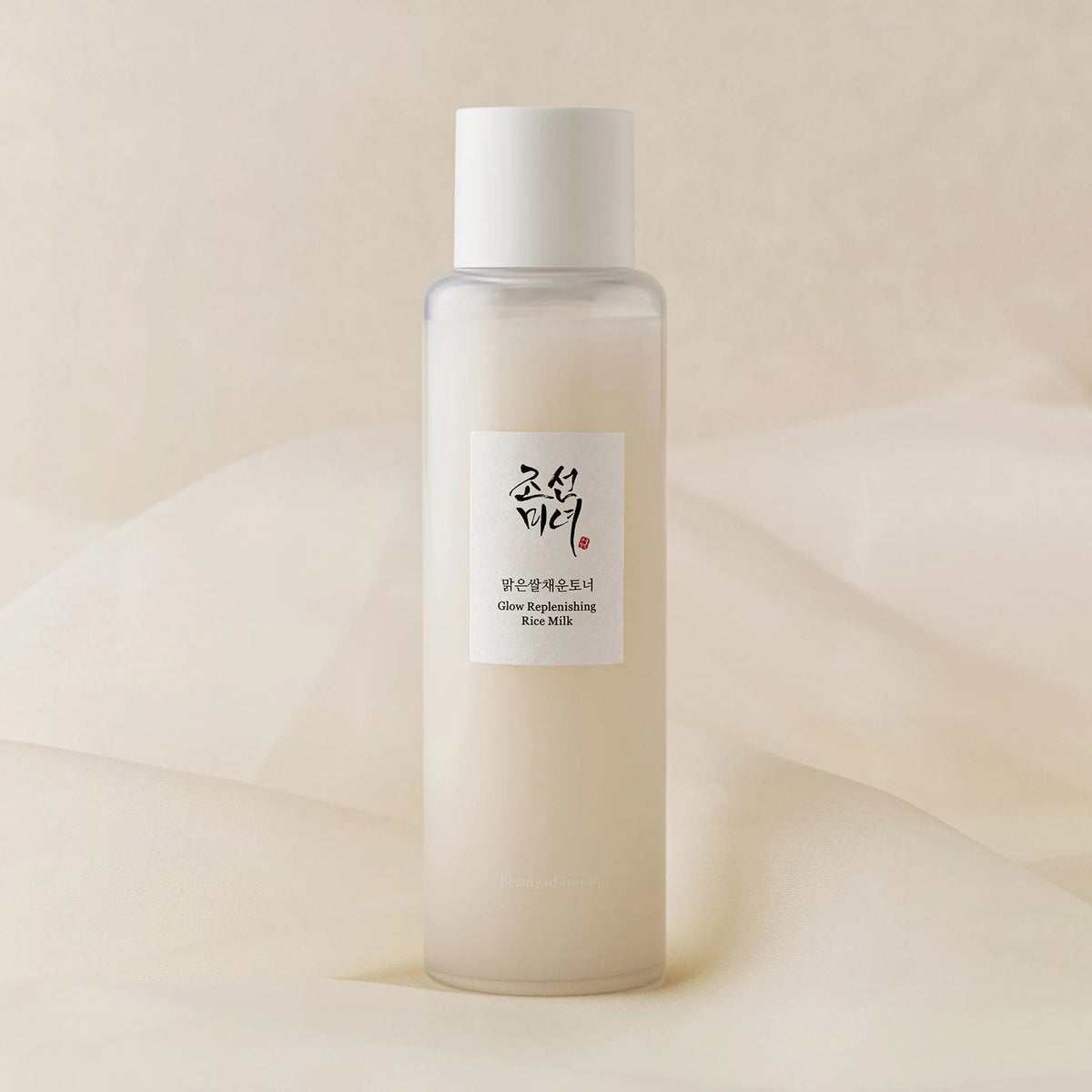 Flasche Glow Repleneshing Rice Milk vor weichem beigem Hintergrund.