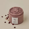 Ein offener Tiegel mit der braunen strukturierten Red Bean Refreshing Pore Mask auf salbeigrüner Oberfläche
