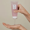 Jemand gibt Red Bean Water Gel vor salbeigrünem Hintergrund aus einer rosa Tube in die Hand