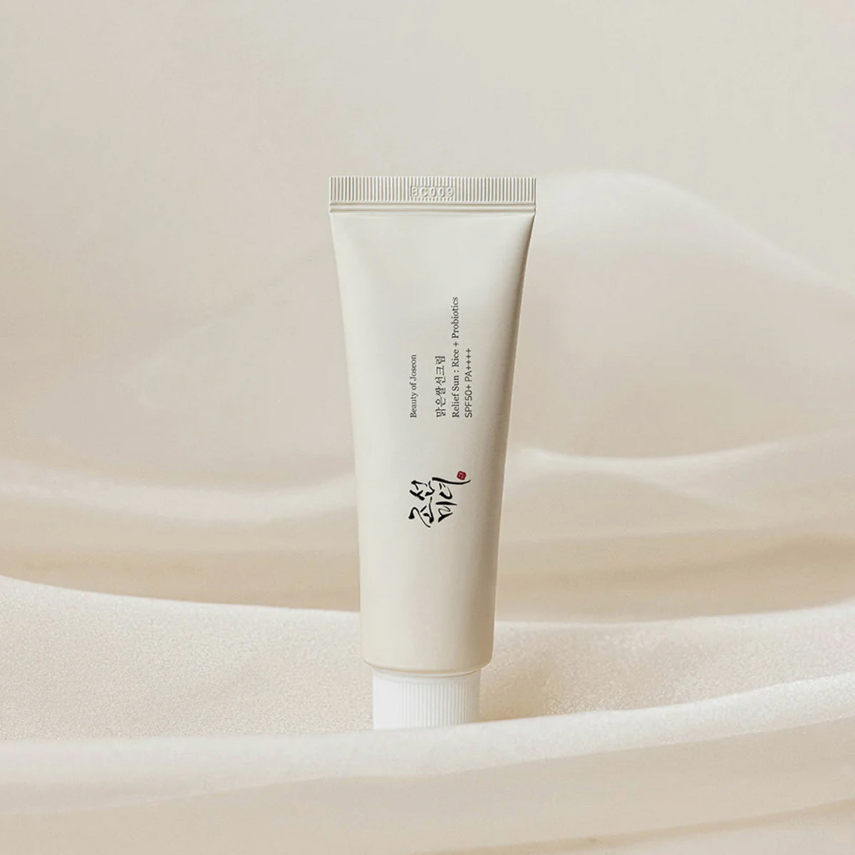 Tube Relief Sun: Rice+Probiotics Sonnencreme vor einem weichen beigen Stoffhintergrund