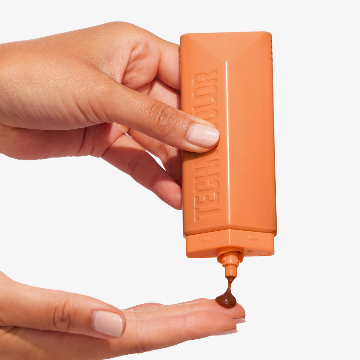 Eine Hand drückt die Technocolor Self Tanning Face Serum aus einer orangefarbenen Flasche auf ihr Fingerspitzen.