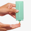 Eine Hand drückt das Technocolor Self Tanning Face Serum Emerald auf die andere Handfläche.