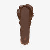 Cremiger Streifen des Cronzer Cream Bronzer in Nutty, ein metallischer Dunkelbraunton, auf weißem Hintergrund.