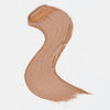 Cremiger Farbstreifen des Catrice Instant Bright Serum Concealers in der Farbe 046W (Warmes dunkles Beige) auf heller Oberfläche.