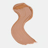 Cremiger Farbstreifen des Catrice Instant Bright Serum Concealers in der Farbe 060N (neutrales dunkles Beige) auf heller Oberfläche.