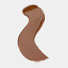 Cremiger Farbstreifen des Catrice Instant Bright Serum Concealers in der Farbe 094W (warmes dunkles Braun) auf heller Oberfläche.
