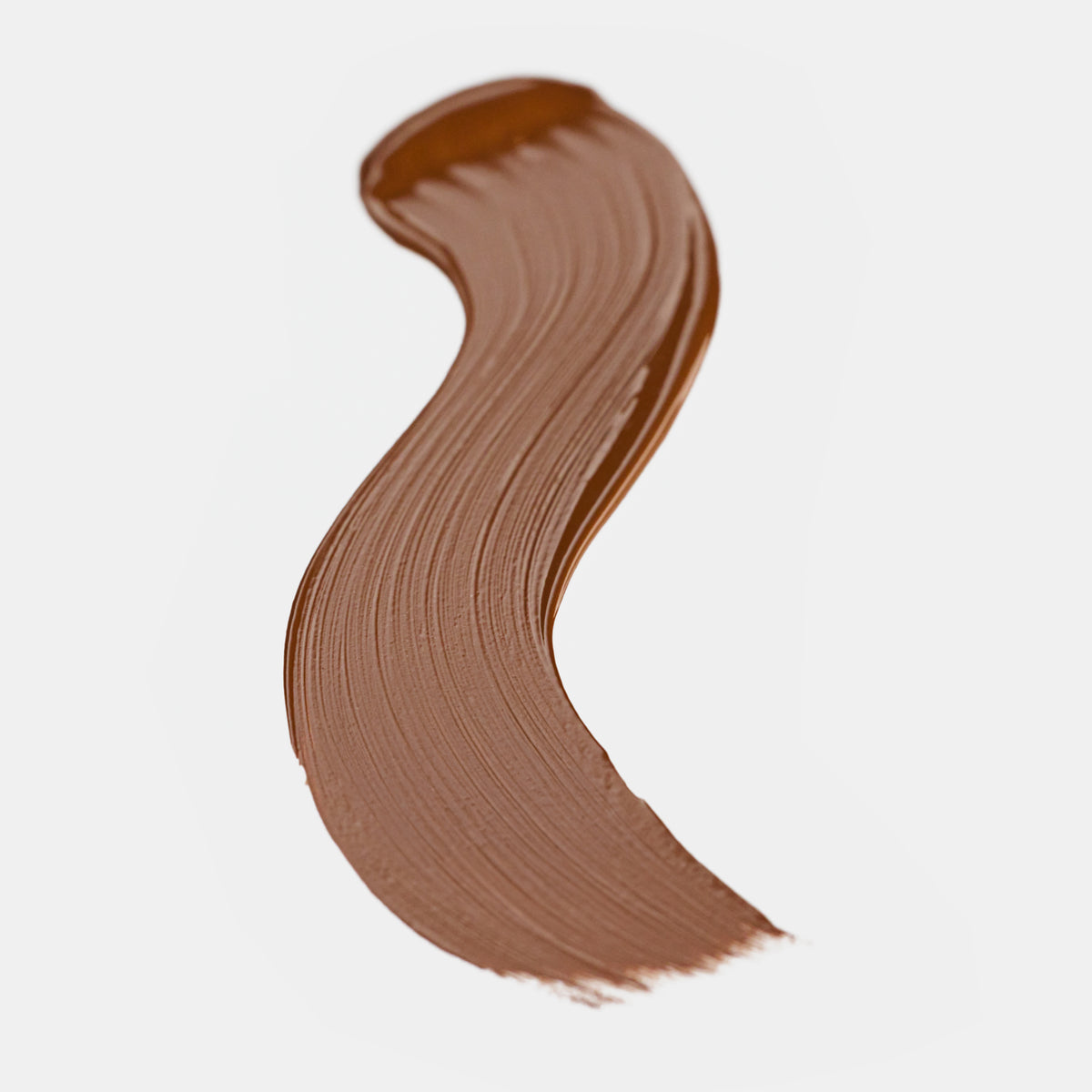 Cremiger Farbstreifen des Catrice Instant Bright Serum Concealers in der Farbe 094W (warmes dunkles Braun) auf heller Oberfläche.