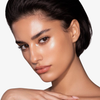 Frau mit strahlender Haut und kurzen dunklen Haaren präsentiert Danessa Myricks Beauty Balm Contour vor einem schlichten Hintergrund.