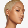 Eine Frau mit kurzen blonden Haaren und strahlender Haut präsentiert Danessa Myricks Beauty Balm Contour vor einem weißen Hintergrund.