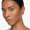 Eine Frau mit glatter, strahlender Haut trägt Danessa Myricks Beauty Balm Contour und blickt selbstbewusst in die Kamera vor einem weißen Hintergrund.