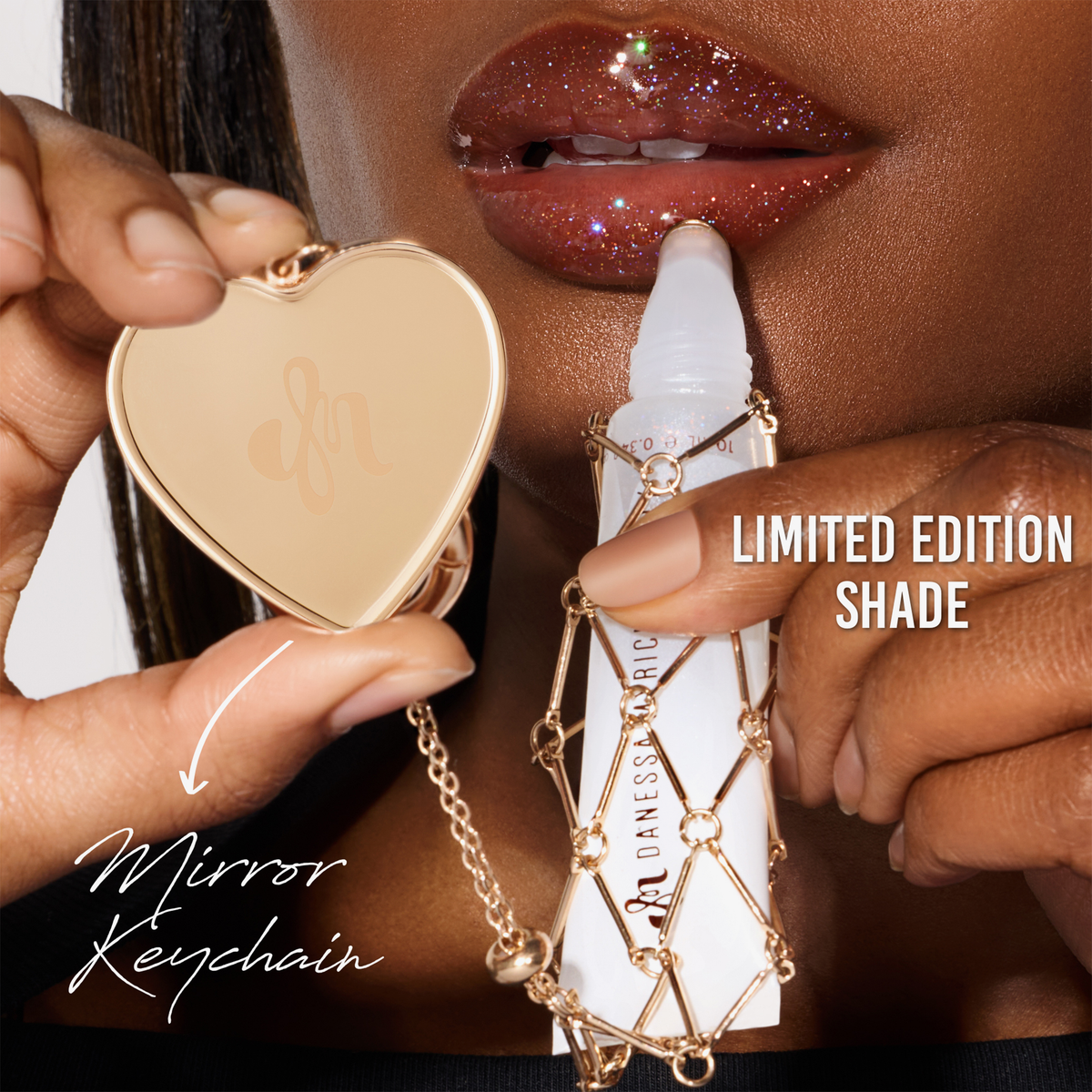 Eine Person mit glitzerndem Lipgloss hält einen herzförmigen Spiegel-Schlüsselanhänger und einen Gloss On Lock Kit-Roll-on in einem goldenen Käfig mit der Aufschrift Limited Edition Shade in der Hand.