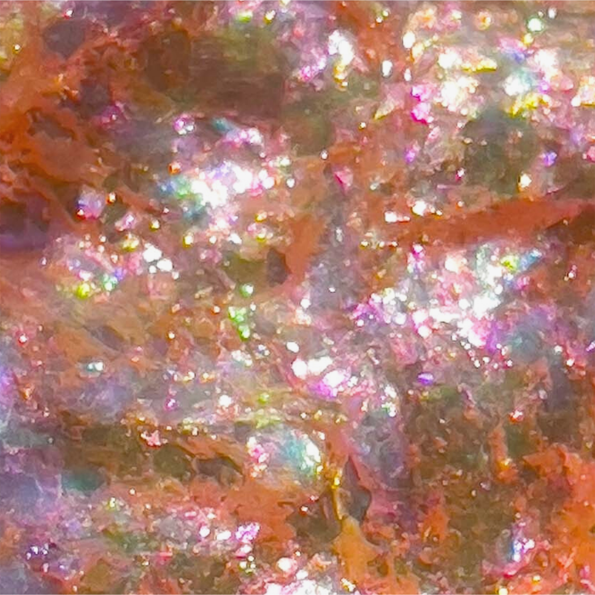 Danessa Myricks Beauty Infinite Chrome Flakes Monarch zeigt ein funkelndes, schillerndes Finish mit rosa, orangefarbenen und violetten Nuancen.