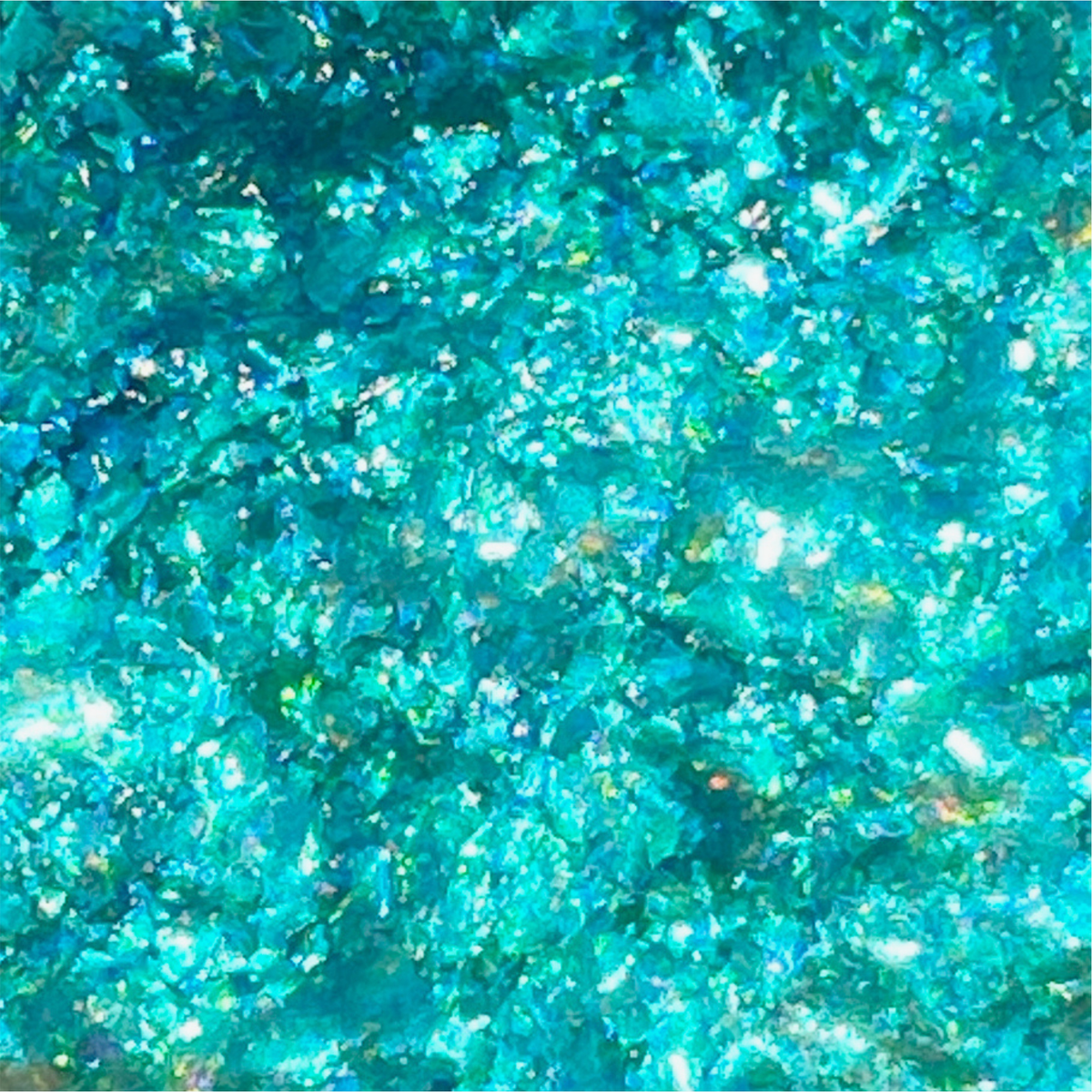 Infinite Chrome Flakes Moonlight von Danessa Myricks Beauty besteht aus schimmernden blau-grünen Kristallen, die das Licht reflektieren und ein funkelndes, strukturiertes Finish erzeugen.