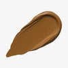 Ein warm-brauner Farbstreifen Yummy Skin Lift & Flex Concealer 12 auf weißem Hintergrund.