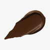 Ein tiefbrauner Farbstreifen Yummy Skin Lift & Flex Concealer 19 auf weißem Hintergrund.