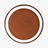 Runde geöffnete Dose Yummy Skin Blurring Balm Powder Lowlighter Off The Grid in tiefem Bronzeton auf weißem Hintergrund.
