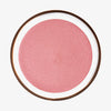 Runder Behälter Yummy Skin Blurring Balm Powder Lowlighter Unbothered mit schimmernd-pinkem Inhalt auf weißem Hintergrund.