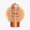 Eine Flasche Yummy Skin Water Powder Serum von Danessa Myricks Beauty mit beigem Serummuster im Hintergrund.