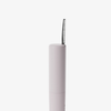 Ein schwarzer Kamm ruht vertikal auf einer hohen, zylindrischen Tube von Dominique Cosmetics Lash Lift Tubing Mascara vor einem weißen Hintergrund.