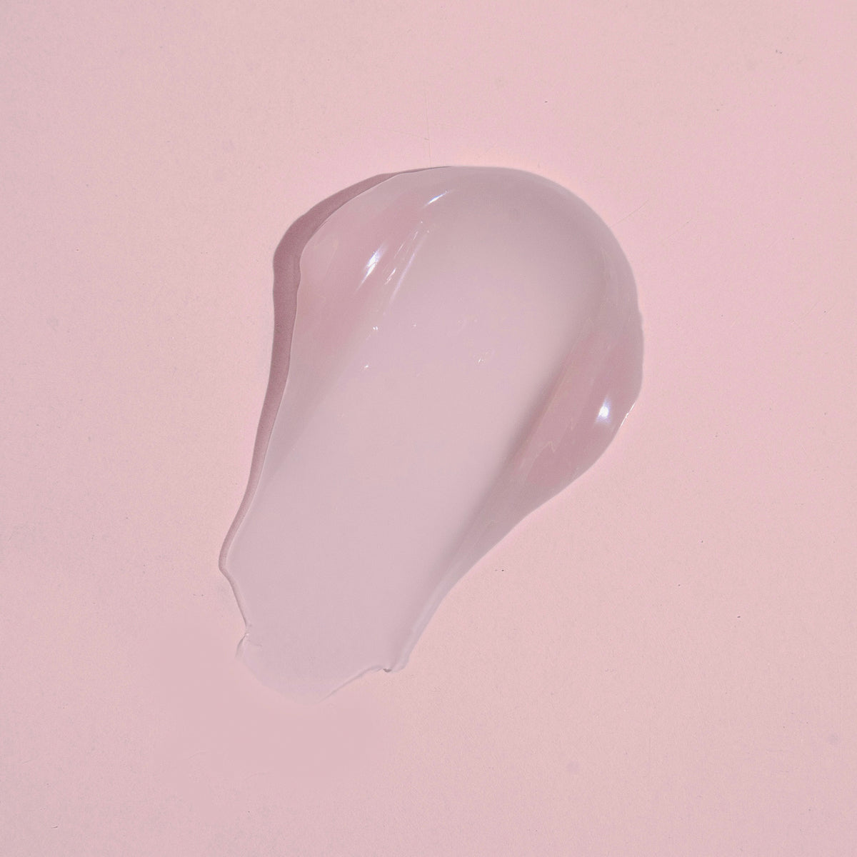 Das klare Gel des Moisture Grip Serum Primer erscheint als Tropfen auf einem hellrosa Hintergrund.