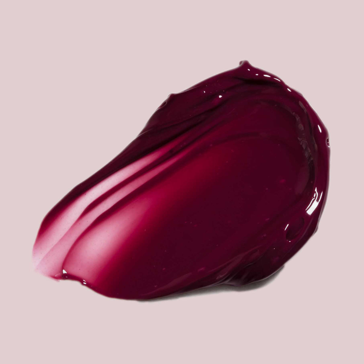 Ein Strich Pillow Soft Hydrating Lip & Cheek Stain in glänzendem Dunkelbeer auf hellbeigem Hintergrund.