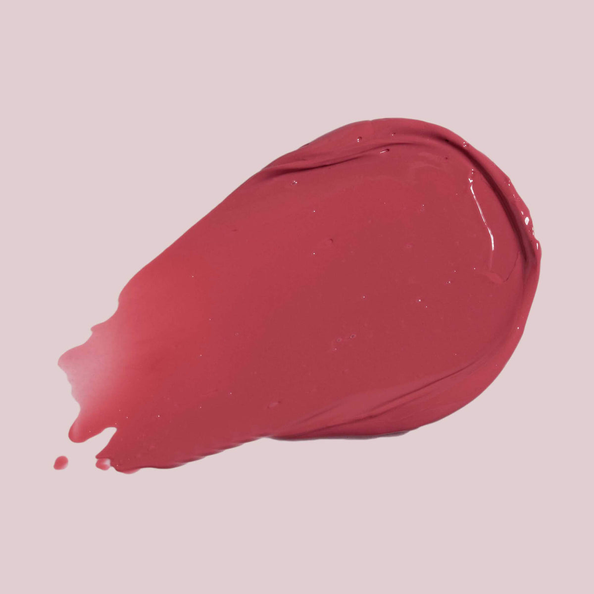 Ein Strich Pillow Soft Hydrating Lip & Cheek Stain in glänzendem Pink auf hellrosa Hintergrund.