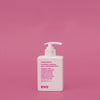 Eine weiße Pumpflasche Mane Tamer Smoothing Conditioner steht vor einem einfarbig rosa Hintergrund.