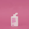 Eine weiße Flasche Mane Tamer Smoothing Shampoo mit Klappdeckel steht vor einem schlichten rosa Hintergrund.