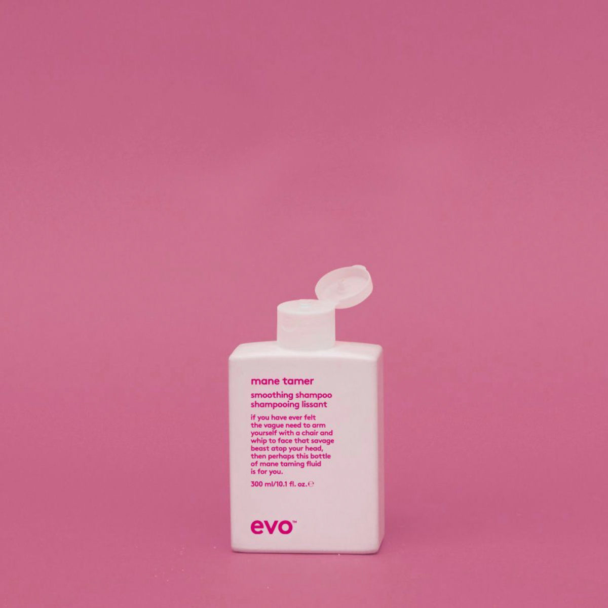 Eine weiße Flasche Mane Tamer Smoothing Shampoo mit Klappdeckel steht vor einem schlichten rosa Hintergrund.