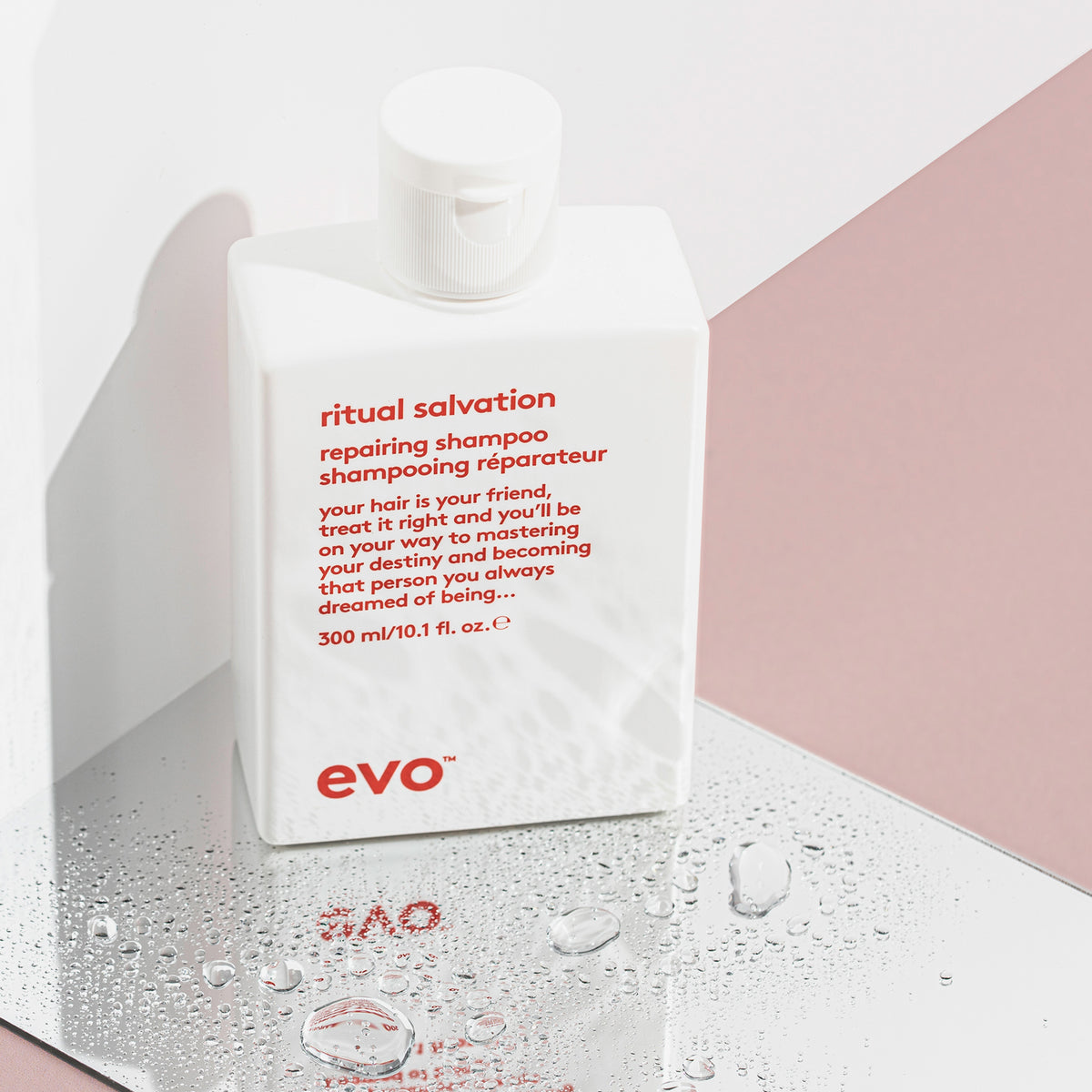 Eine weiße Flasche Ritual Salvation Repairing Shampoo steht auf einer reflektierenden Oberfläche mit Wassertropfen.